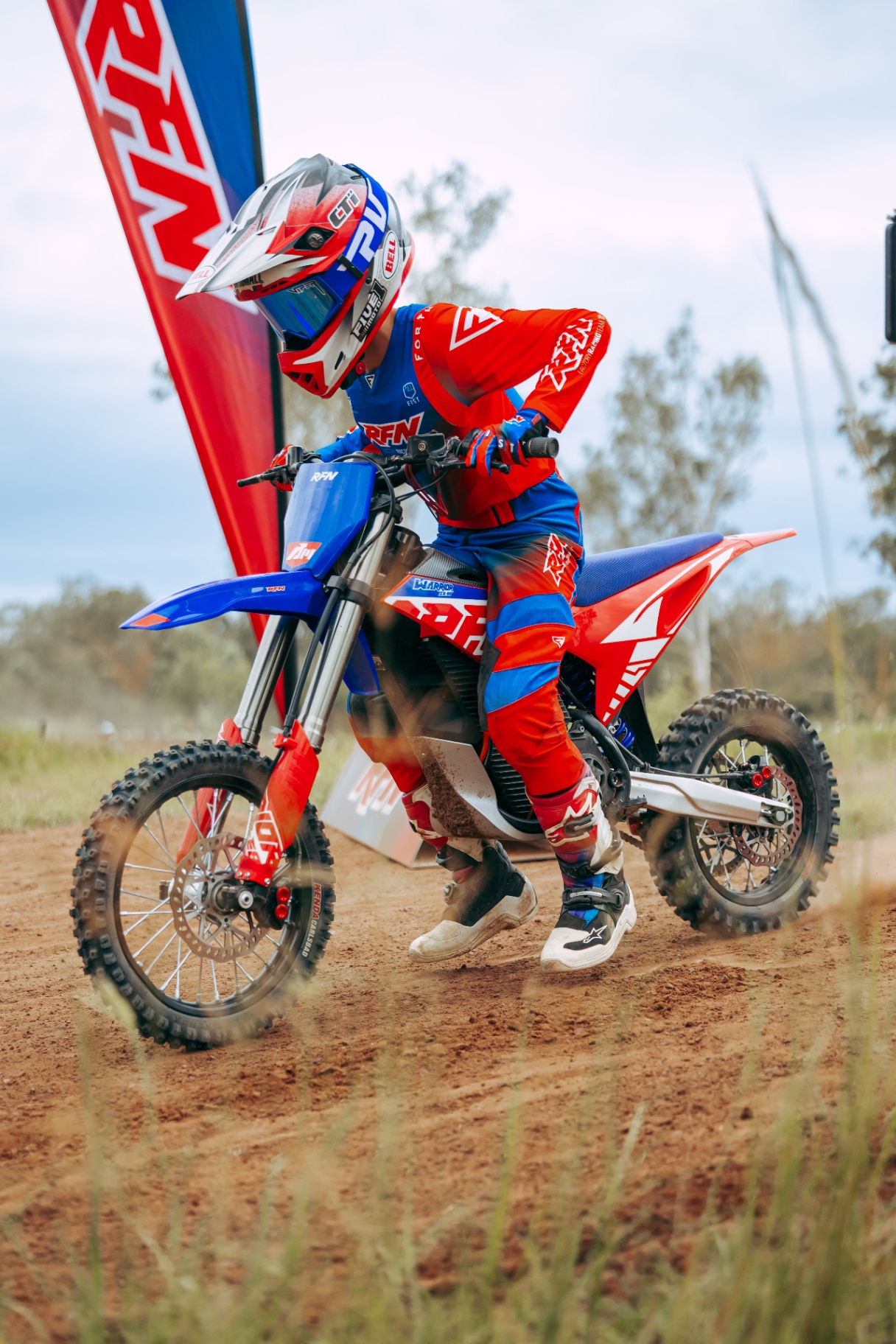 RFN Warrior SX-E8 — jeździec na starcie z flagą RFN, elektryczny cross w barwach RFN Factory Racing